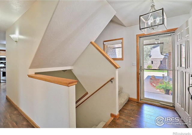 foyer featuring hardwood / wood-style floors, baseboards, a notable chandelier, and stairway