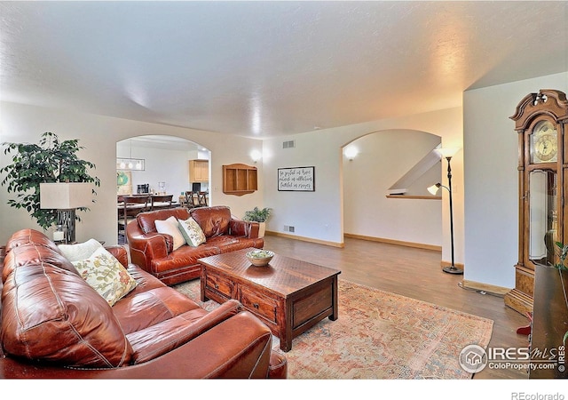 living area with visible vents, baseboards, arched walkways, and wood finished floors