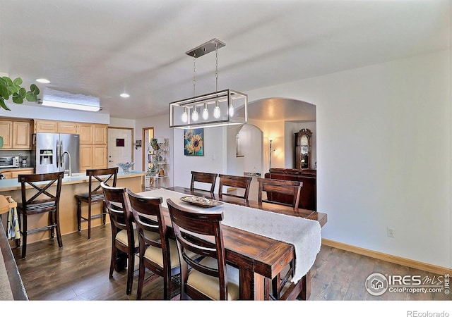 dining room with dark wood-type flooring, baseboards, recessed lighting, and arched walkways