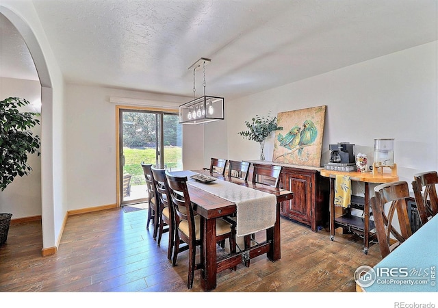 dining area featuring a chandelier, baseboards, arched walkways, and hardwood / wood-style floors