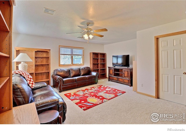 living room with carpet floors, a ceiling fan, and visible vents