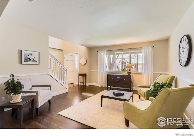 living room featuring dark wood-type flooring, baseboards, and stairway