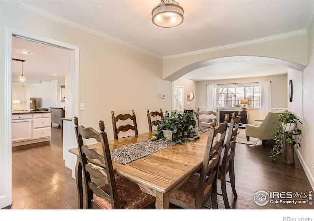 dining room featuring crown molding, arched walkways, and wood finished floors