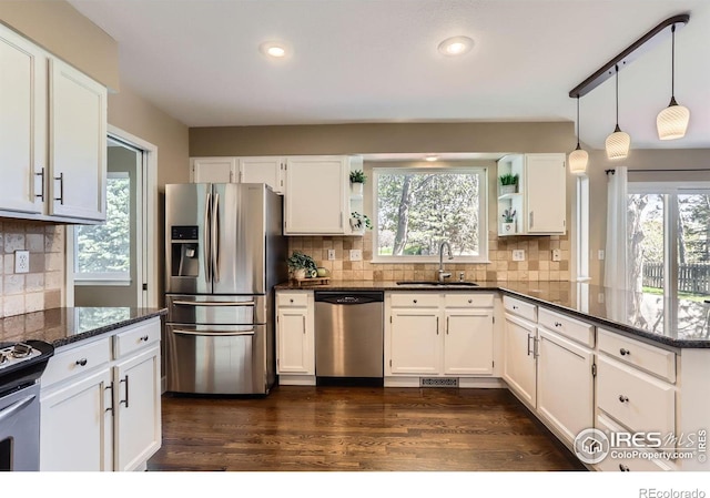 kitchen featuring white cabinets, open shelves, a sink, appliances with stainless steel finishes, and dark stone counters