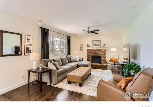 living area featuring a brick fireplace, baseboards, a ceiling fan, and wood finished floors