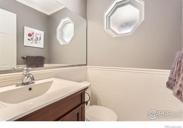 bathroom featuring tile walls, toilet, a wealth of natural light, and vanity