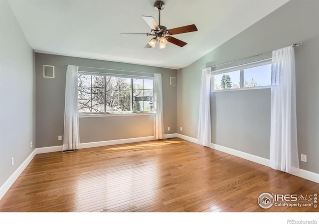 unfurnished room with hardwood / wood-style floors, baseboards, a ceiling fan, and vaulted ceiling