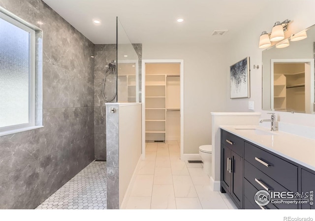 full bathroom featuring vanity, walk in shower, toilet, a walk in closet, and visible vents