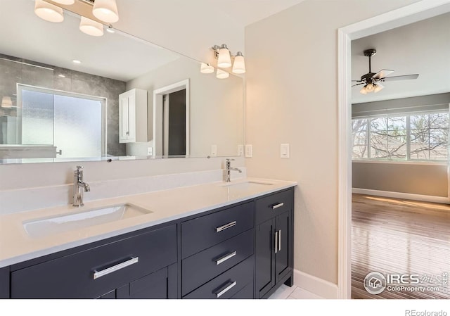 full bathroom with double vanity, baseboards, a sink, and ceiling fan