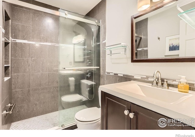 bathroom featuring a shower stall, vanity, tile walls, and toilet