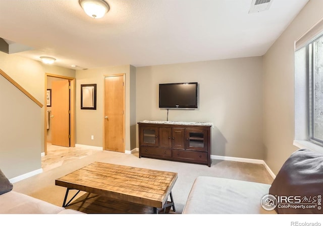living room featuring visible vents, baseboards, and light carpet