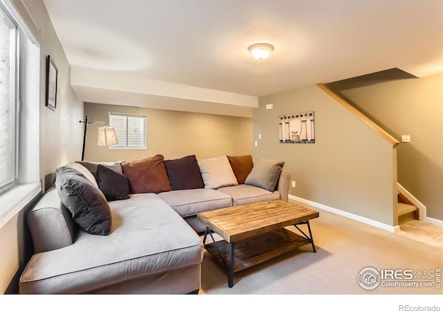 carpeted living area with baseboards, plenty of natural light, and stairs