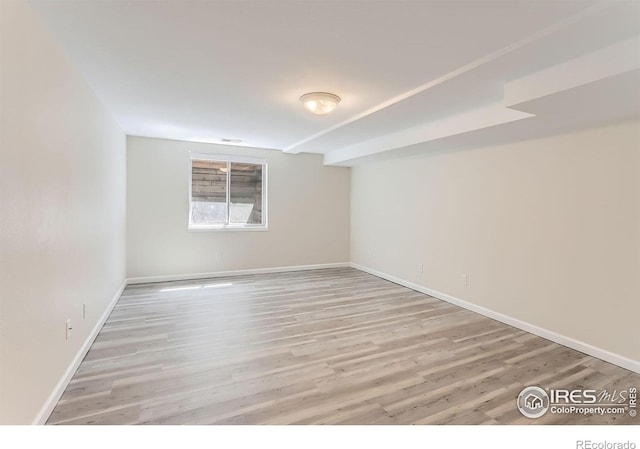 empty room with visible vents, light wood-style flooring, and baseboards