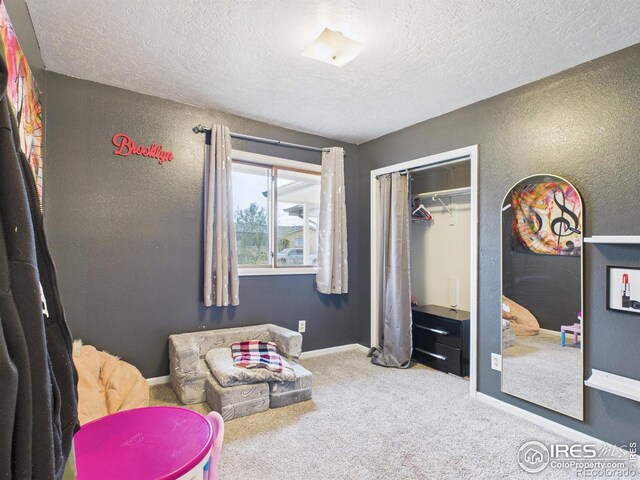 carpeted bedroom featuring a closet, a textured ceiling, baseboards, and a textured wall