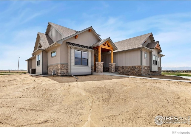 craftsman inspired home with central AC unit, stone siding, and a shingled roof