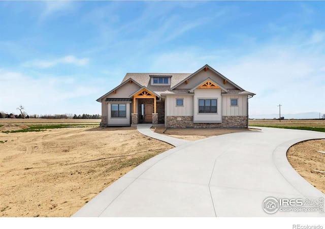craftsman house with board and batten siding, a shingled roof, and stone siding