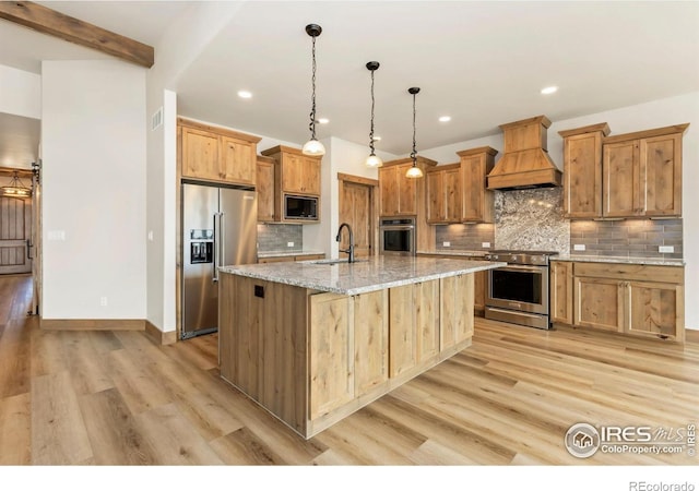 kitchen featuring premium range hood, backsplash, appliances with stainless steel finishes, light wood finished floors, and a sink
