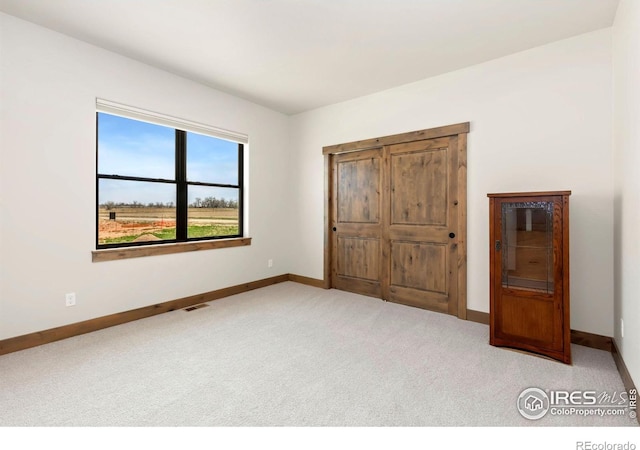 unfurnished bedroom with light colored carpet, baseboards, and visible vents