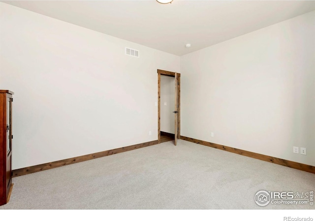 carpeted spare room with visible vents and baseboards