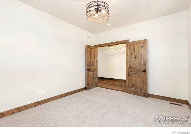 carpeted spare room featuring visible vents and baseboards