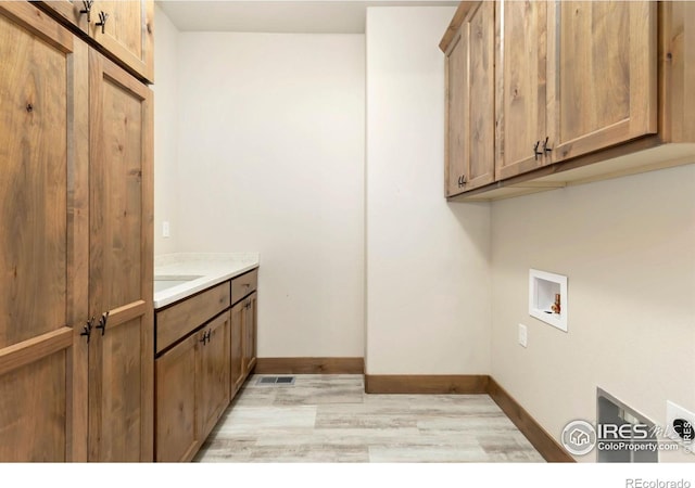 laundry room with light wood-type flooring, baseboards, hookup for a washing machine, and cabinet space