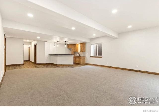 unfurnished living room with baseboards, recessed lighting, carpet flooring, beamed ceiling, and bar