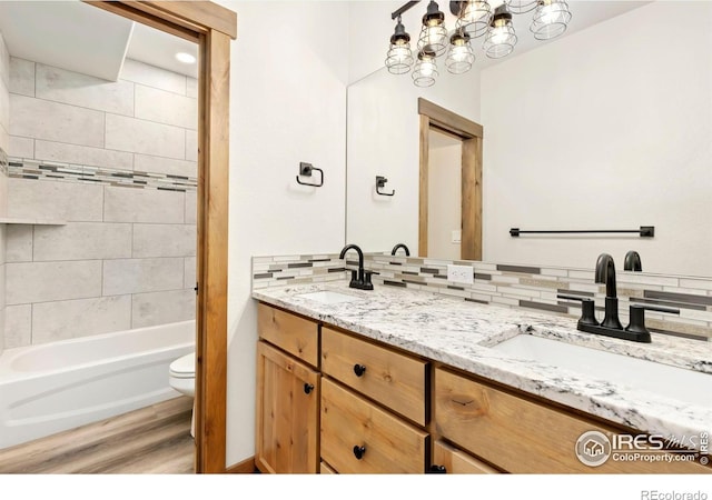 bathroom with toilet, wood finished floors, double vanity, and a sink