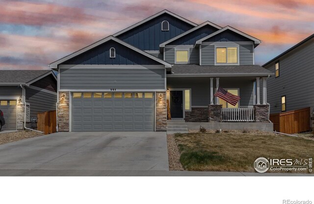 craftsman-style house with board and batten siding, stone siding, concrete driveway, and covered porch