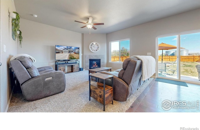 living area featuring a ceiling fan, wood finished floors, and a tiled fireplace