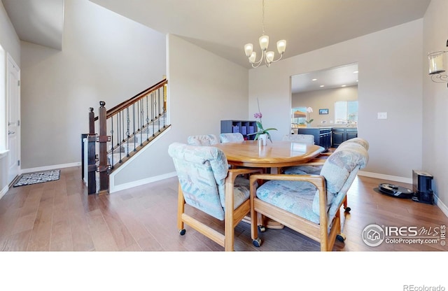 dining room with baseboards, wood finished floors, an inviting chandelier, and stairway