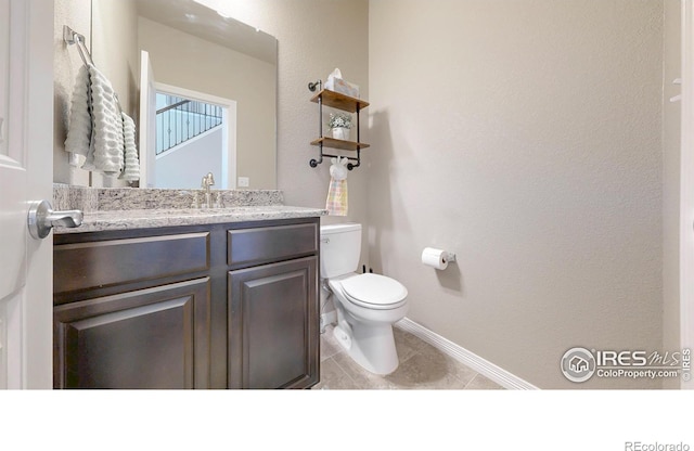 half bathroom featuring baseboards, vanity, tile patterned floors, and toilet