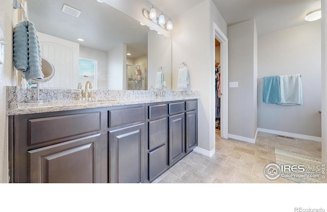 full bath with a sink, double vanity, baseboards, visible vents, and a shower stall