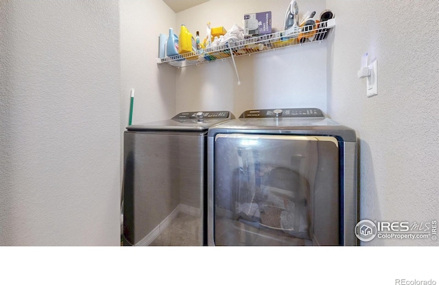 washroom with washer and dryer, a textured wall, and laundry area