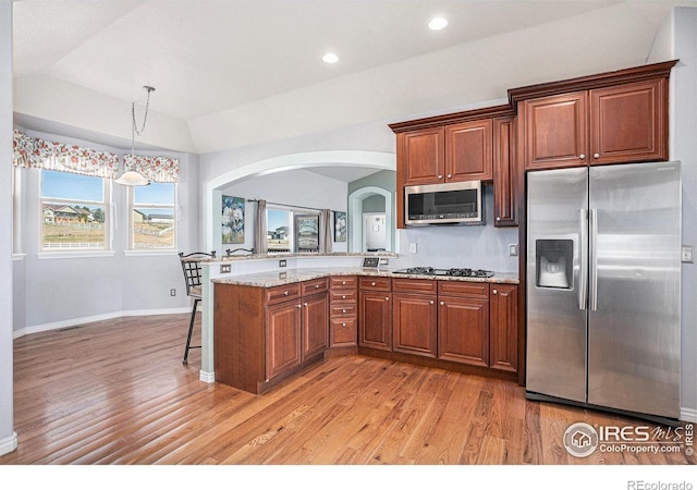 kitchen with lofted ceiling, stainless steel appliances, a peninsula, and light wood-style floors