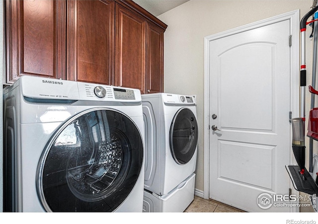 laundry area featuring cabinet space, washing machine and clothes dryer, and light tile patterned flooring
