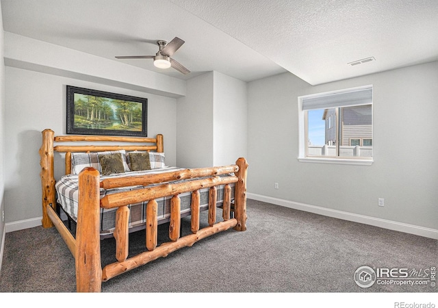 carpeted bedroom with a textured ceiling, visible vents, a ceiling fan, and baseboards