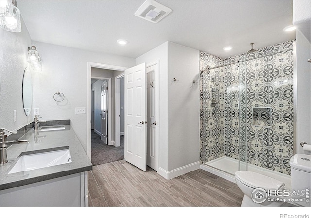 full bath featuring a sink, toilet, visible vents, wood finished floors, and a shower stall