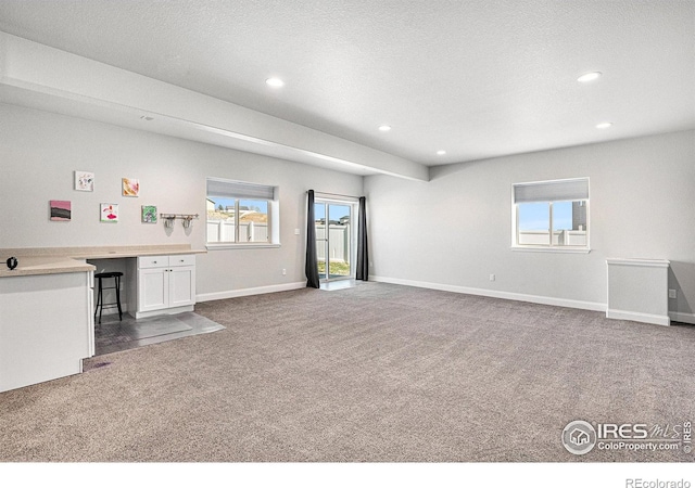 unfurnished living room with dark carpet, baseboards, and recessed lighting