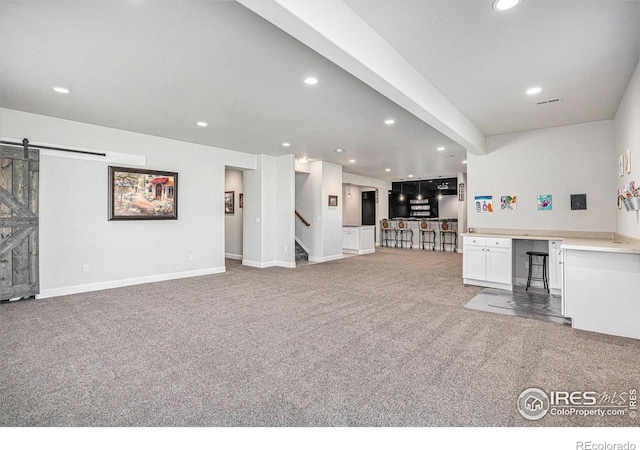 carpeted living room featuring recessed lighting, visible vents, baseboards, and a barn door