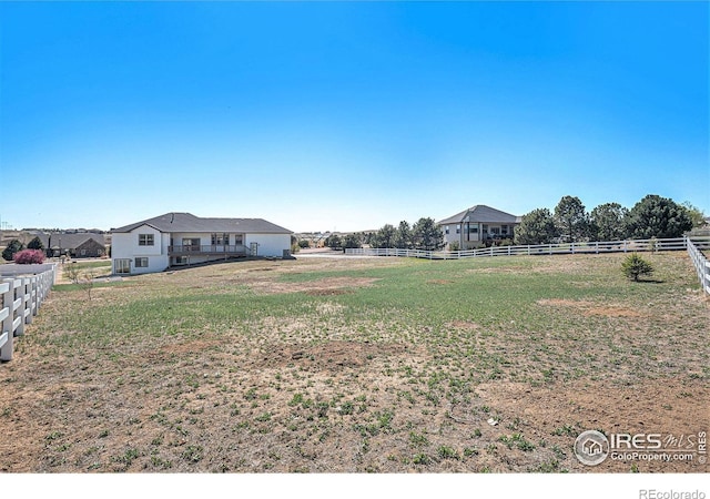 view of yard with fence and a rural view