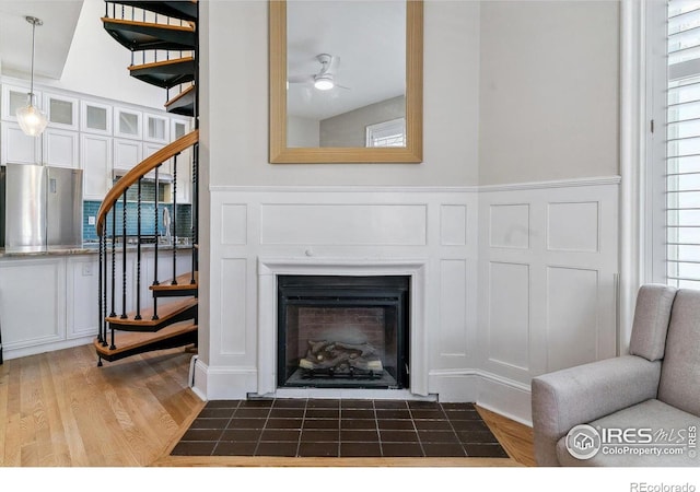 details with a fireplace with flush hearth, wood finished floors, a decorative wall, and ceiling fan