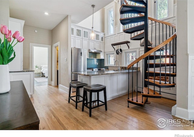 kitchen featuring glass insert cabinets, white cabinetry, light wood-style floors, and freestanding refrigerator
