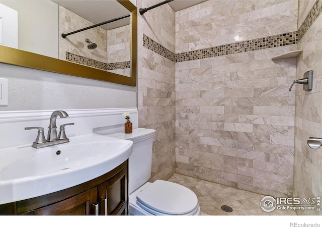 full bath with toilet, vanity, and a tile shower