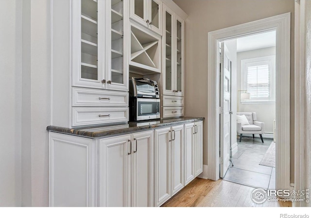 kitchen featuring white cabinets, light wood-style floors, and glass insert cabinets