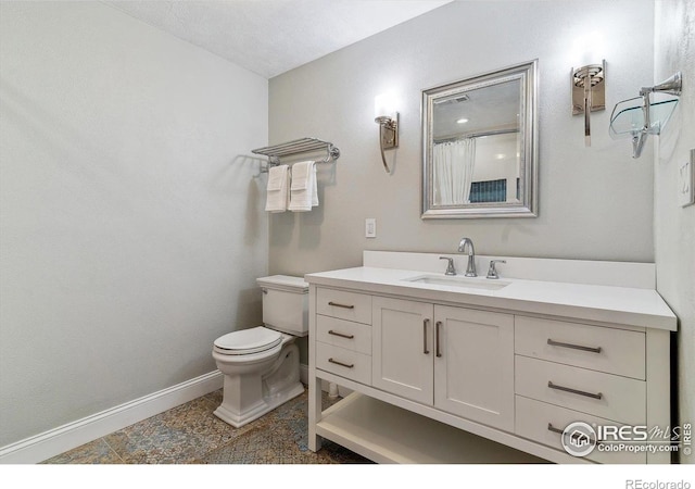 bathroom featuring baseboards, toilet, and vanity