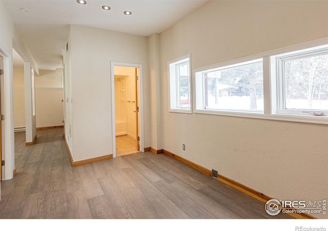 unfurnished bedroom featuring baseboards, light wood-style floors, ensuite bathroom, and recessed lighting