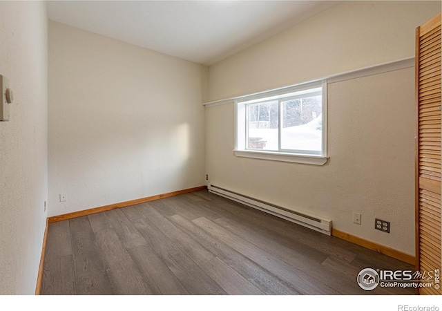 empty room with baseboards, wood finished floors, and baseboard heating