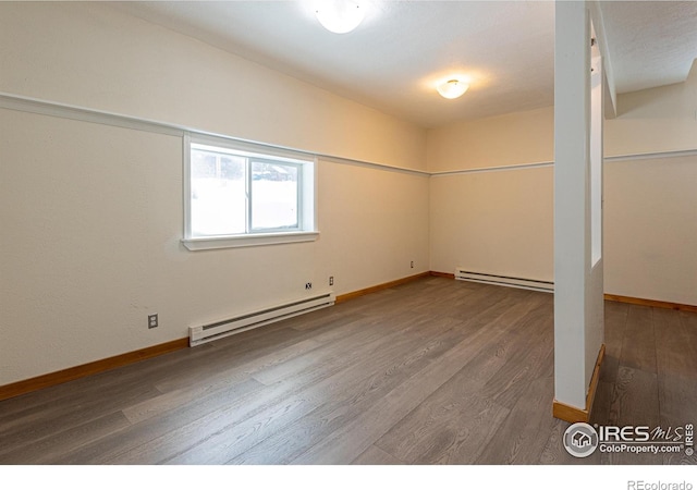 below grade area with a baseboard heating unit, wood finished floors, and baseboards