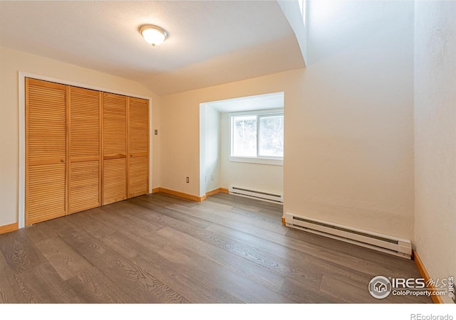 unfurnished bedroom with baseboard heating, wood finished floors, and a closet