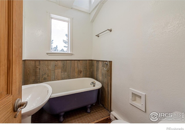 bathroom featuring wainscoting, a sink, and a freestanding bath
